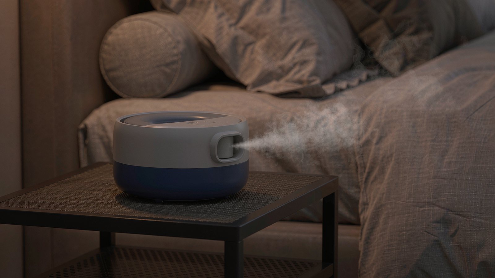A small ultrasonic humidifier releasing a soft mist on a bedside table in a warm bedroom during the evening